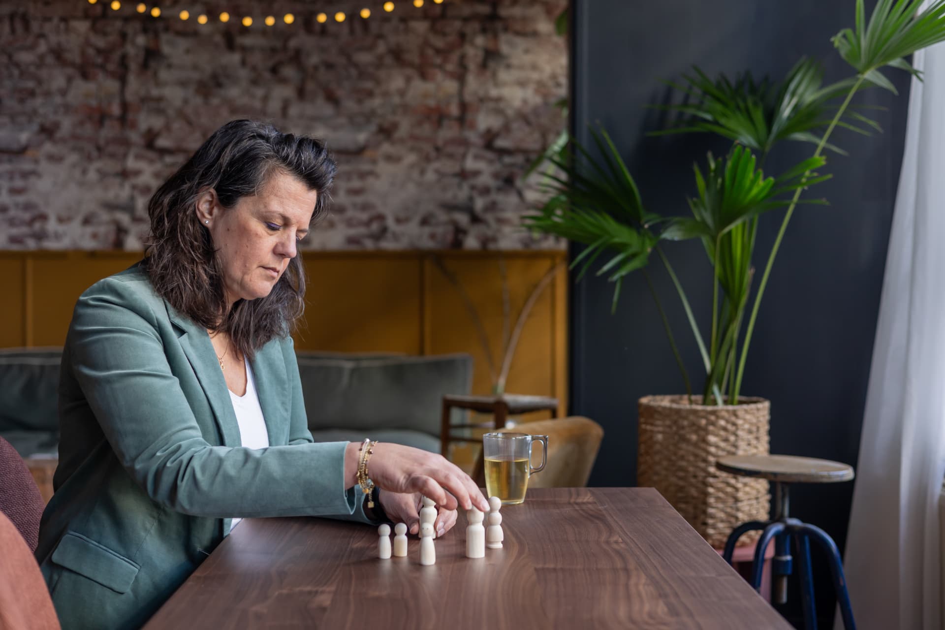 Mathilda zet houten poppetjes neer aan een tafel, als bij een familieopstelling