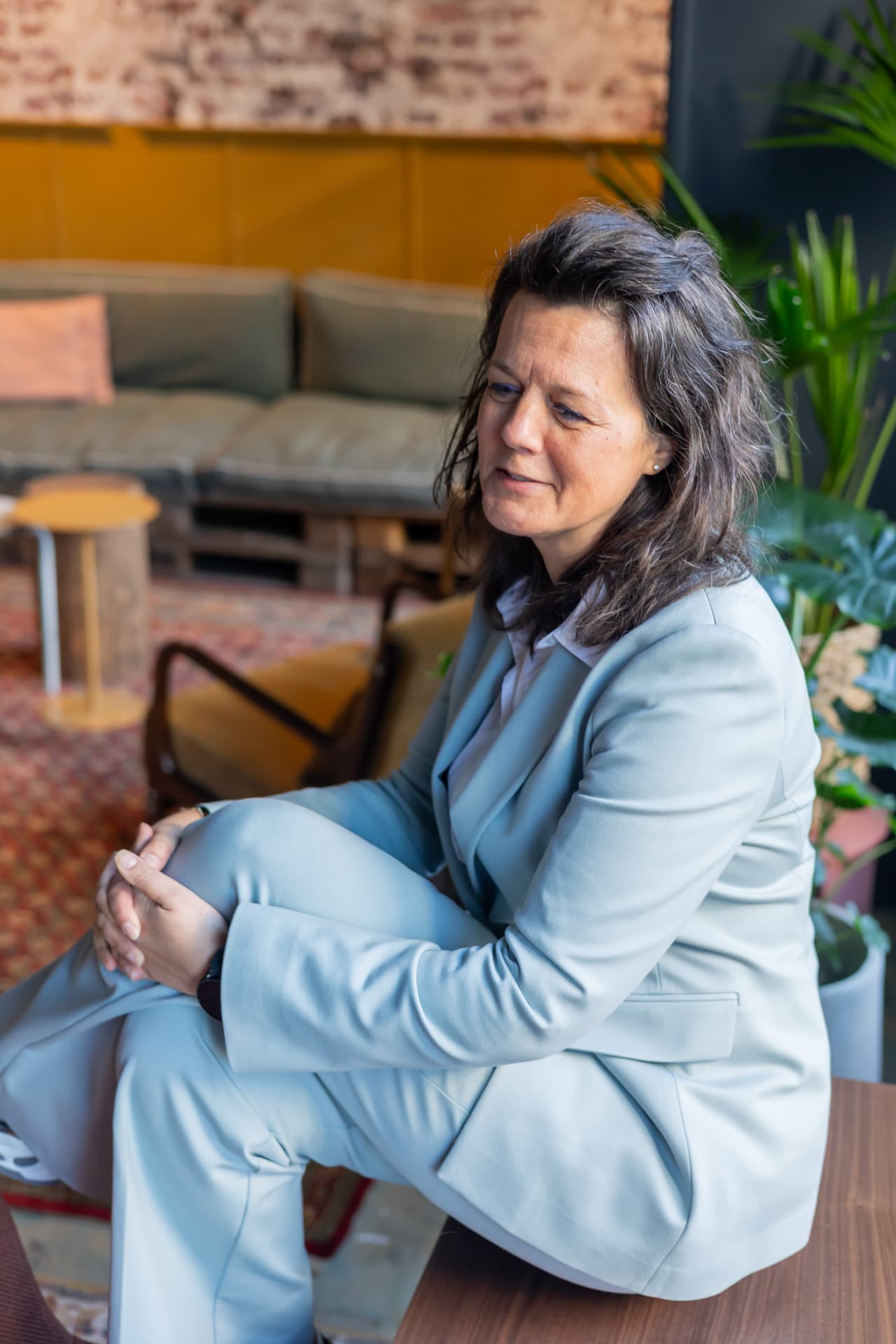 Mathilda van den Hof zittend in een lichte ruimte, in een lichtblauw pak