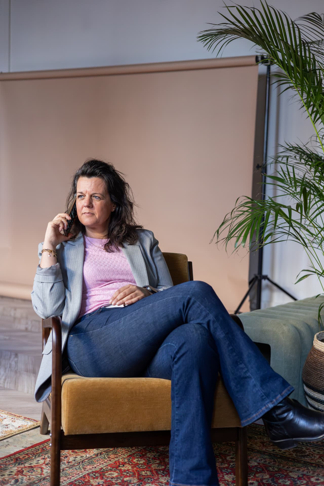 Mathilda van den Hof zit met een telefoon aan haar oor in haar werkruimte